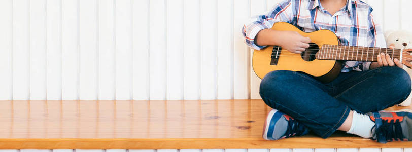 孩子在家里弹吉他。音乐教育与课外课程