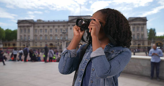在白金汉宫外用相机拍照的兴奋游客画像