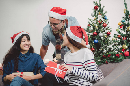 圣诞晚会与朋友, 亚洲人交换礼物和赠送礼物与笑脸, 节日圣诞庆祝概念