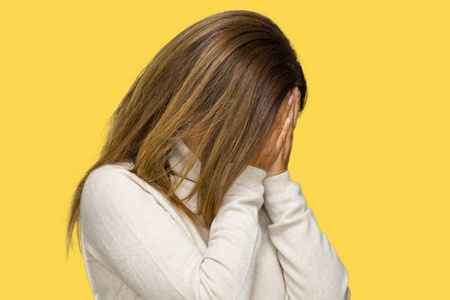 美丽的中年成年妇女穿着冬季毛衣在孤立的背景与悲伤的表情覆盖脸与手