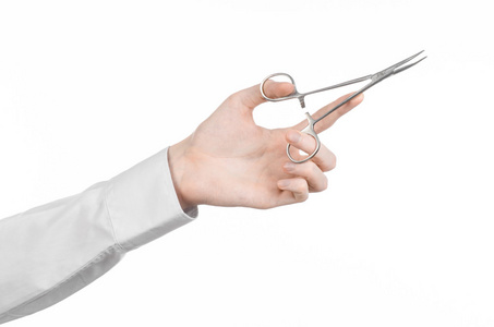 手术和医疗主题 医生的手中拿着手术夹剪刀分离在工作室中的白色背景上的白大褂