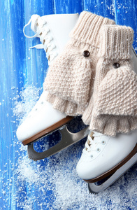 羊毛断指手套和木制背景上的花样滑冰冰鞋