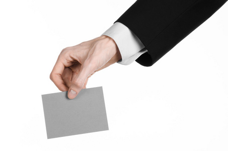 业务和广告主题 孤立在工作室中的白色背景上的手里拿着一个灰色的空白卡的黑色西装的男人