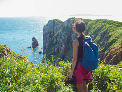 年轻女子独自站在岩石悬崖上, 女孩旅游摄影师在美丽的野生动物的背景