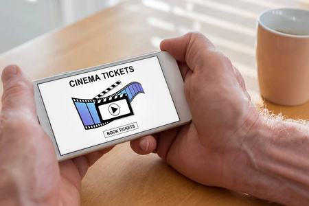 男性手持带有在线电影票预订概念的智能手机