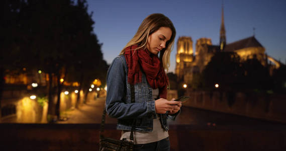 巴黎时尚女孩晚上在智能手机上发短信