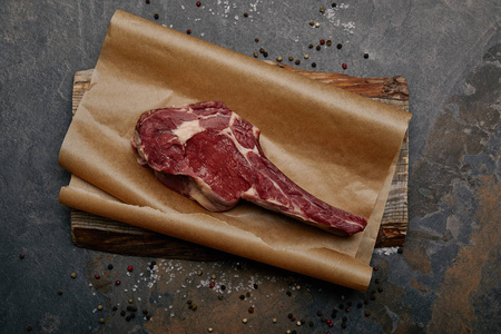 在灰色背景上的烤纸上, 用香料看到了生肋骨眼牛排的顶视图