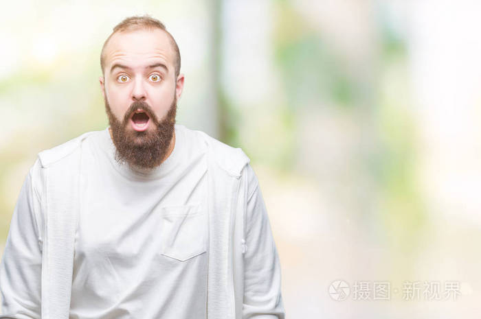 年轻的高加索嬉皮士男子穿着运动服在孤立的背景害怕和震惊与惊奇的