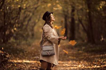 美丽时尚的妇女与时尚化妆在秋季公园穿着帽子和大衣