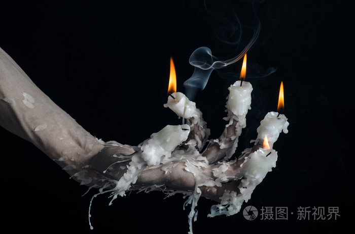 万圣节主题: 手戴着一根蜡烛和滴熔化的蜡在黑色上分离背景