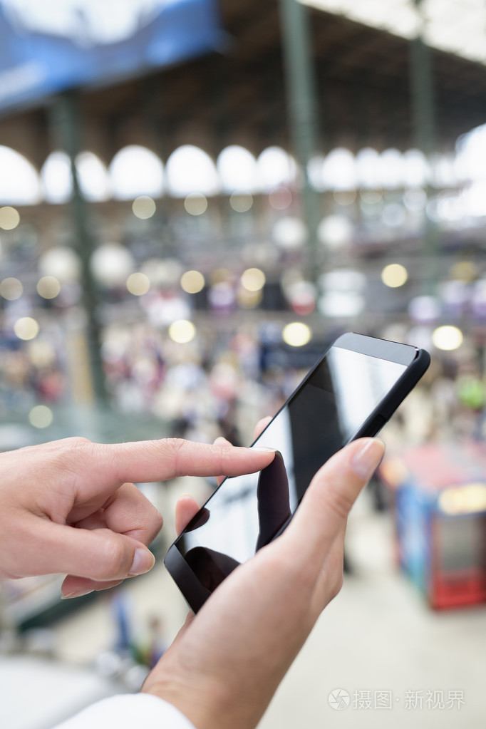 手女人用她的手机在车站,背景的特写
