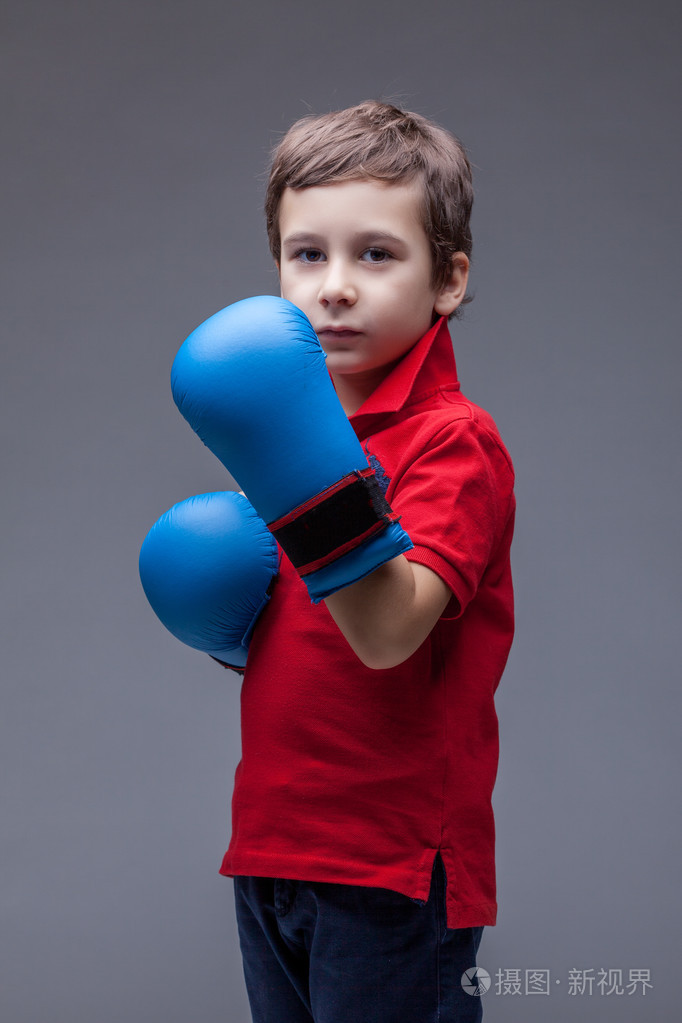 严重英俊的男孩在拳击手套摆姿势