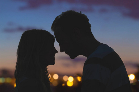 在背景下与城市全景接吻的一对年轻情侣的剪影