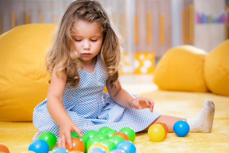 可爱的白种孩子坐在地毯和演奏五颜六色的球在幼稚园