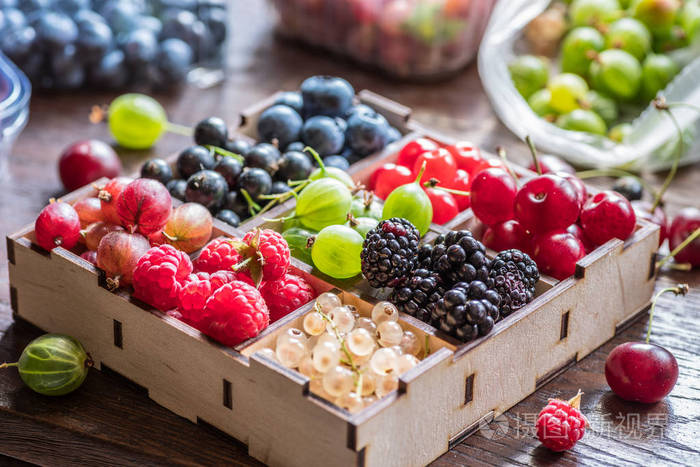 在桌子上的木制板条箱五颜六色的浆果。一些浆果靠近盒子