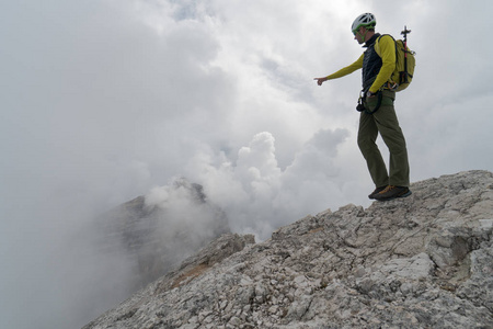 青年男性山指南在白云岩山顶指向风景和解释看法