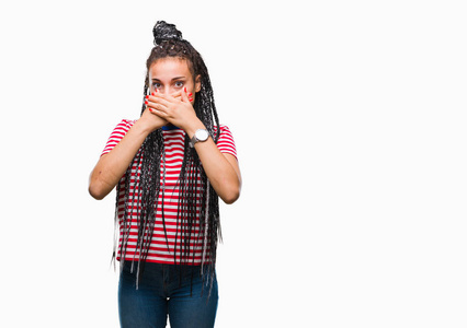 年轻的编织头发非洲美国女孩在孤立的背景震惊覆盖嘴与手的错误。秘密概念
