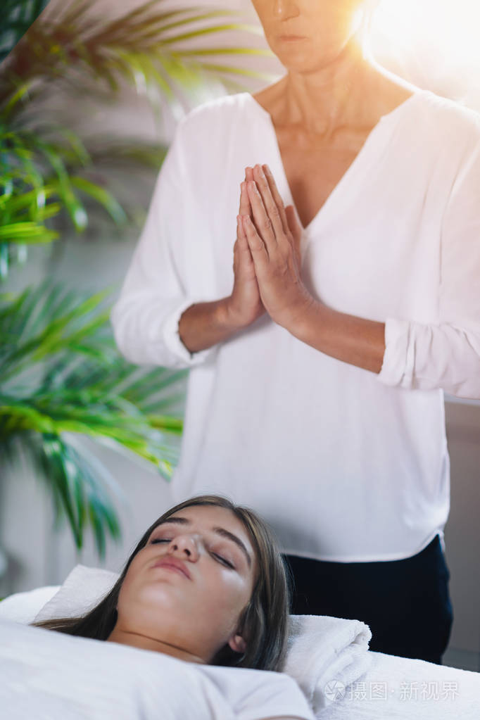 灵气医生站在病人的身体上方祈祷