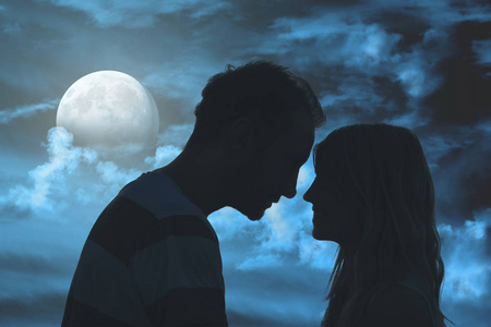 一对年轻夫妇的剪影在月光下的天空下