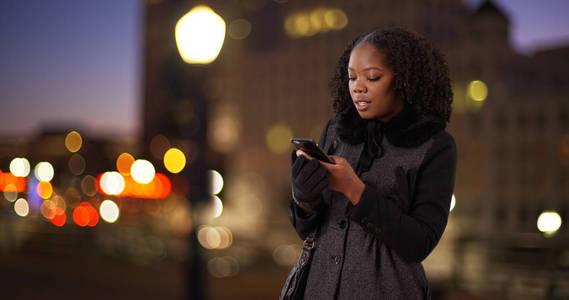 快乐的非洲裔美国妇女千年在城市的夜间短信