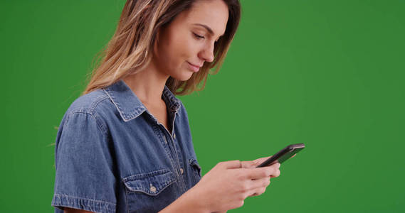 在绿色屏幕上的智能手机上有吸引力的千年女孩消息特写镜头