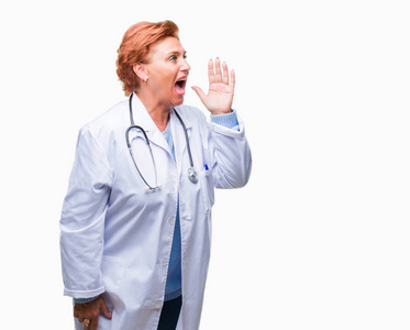 高级高加索医生妇女穿着医疗制服在孤立的背景下大喊大叫, 大声尖叫着, 手放在嘴边。沟通理念
