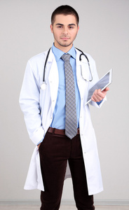 男医生站与灰色的背景上的文件夹