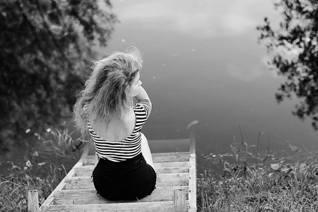 美丽的悲伤的女人坐在河岸上