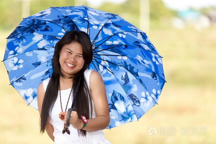 年轻漂亮的泰国姑娘在蓝色的遮阳伞下