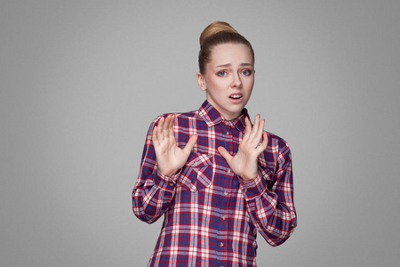 害怕美丽的金发碧眼的女人在粉红色格子衬衫与收集面包发型看着相机