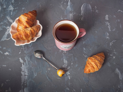 清淡的早餐, 新鲜的羊角面包和咖啡在粉红色的杯子, 一茶匙
