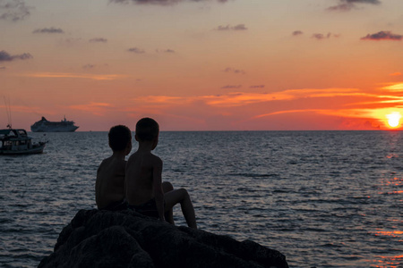 两个男孩的剪影在晚上海风景图片
