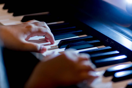 有选择的焦点, 儿童手指和钢琴键弹钢琴与照明。有用于音乐会或学习音乐的乐器