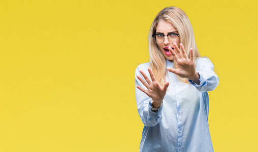 年轻漂亮的金发女郎戴着眼镜在孤立的背景下害怕和恐惧的表情用手停止