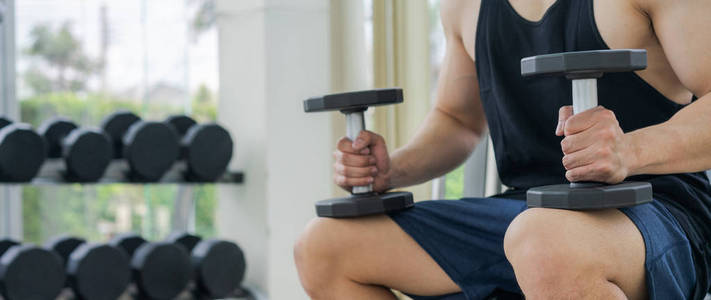 肌肉的男人健美在健身房训练哑铃。健康的生活方式和健美理念