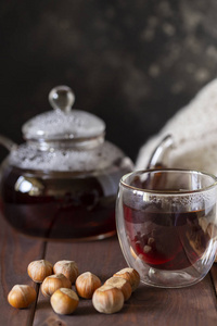 茶在玻璃杯与茶壶和针织毯附近, 与榛子在木材背景