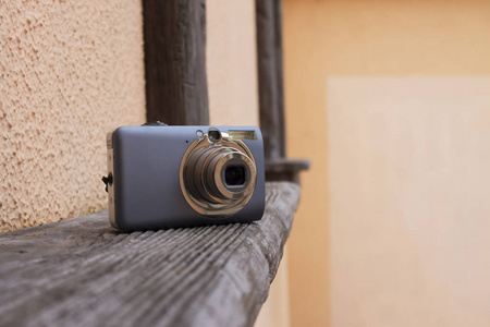 小, 灰色数字袖珍照相机在木架子与粉红色背景  外面