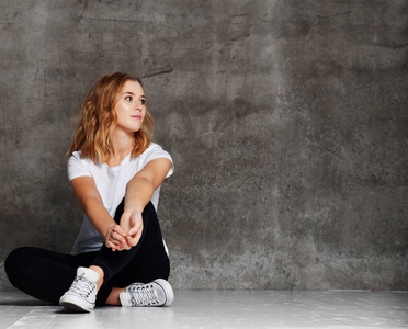 艾希普希特穿着白色白色 t恤的希普斯特女孩, 牛仔裤靠墙照片