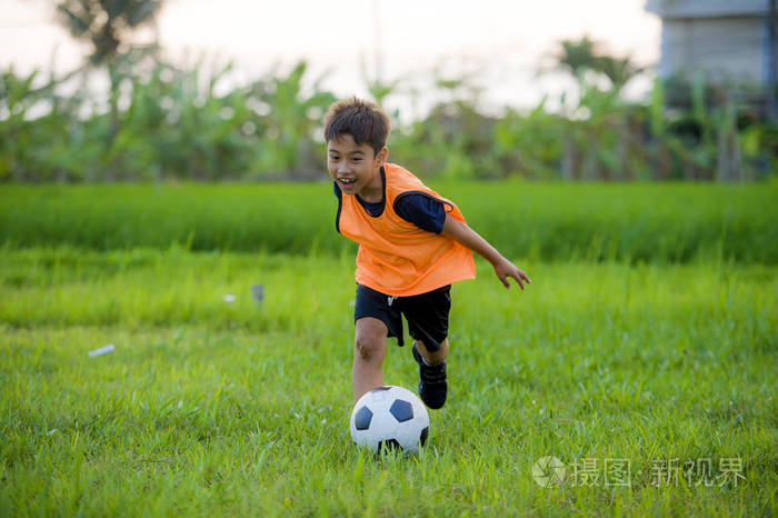 8或9岁的快乐和兴奋的孩子踢足球户外在花园穿着训练背心运行和踢足球