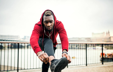 一个年轻的运动黑人跑步者在一个城市外系鞋带