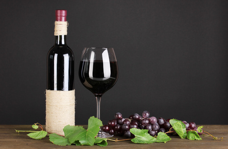 在黑色背景上的木桌上瓶酒用葡萄叶