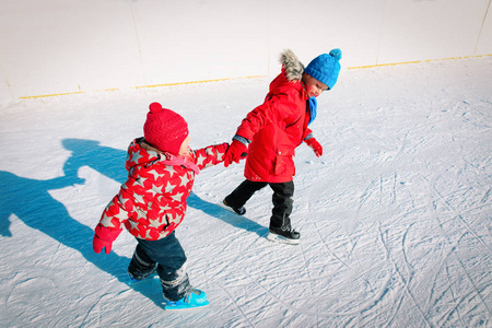 小男孩和女孩一起滑冰,孩子们的冬季运动照片