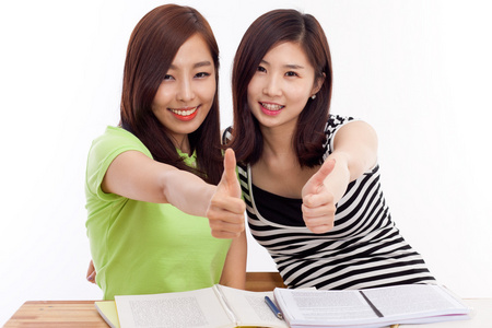 年轻的亚洲学生妇女在桌子上显示的拇指
