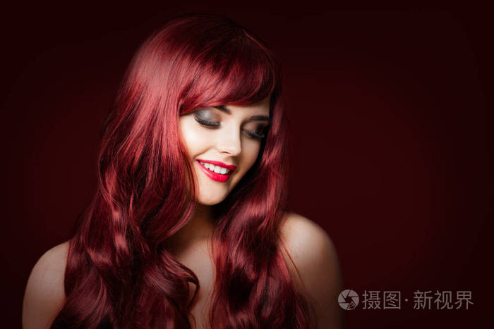 微笑的红发女人时尚模特在深红色背景.化妆, 完美的波浪形发型