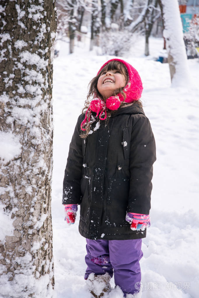 小女孩在夹克和针织帽子捕捉雪花在冬季公园圣诞节.