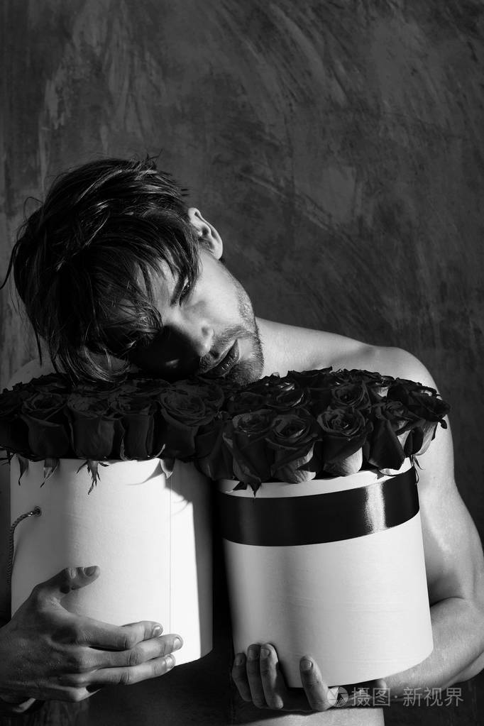 大胡子肌肉男与性感的身体拥有玫瑰的红盒子