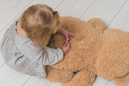 女孩, 一个孩子扮演医生, 做一个注射胰岛素玩具熊