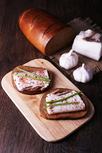 在砧板上的猪油与大蒜对木制背景的三明治
