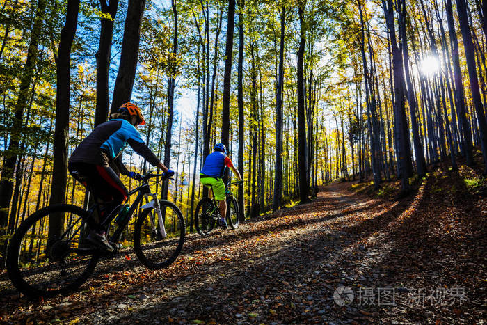 骑自行车的妇女和男子在贝斯基蒂山区秋天森林景观骑mtb内室赛道的