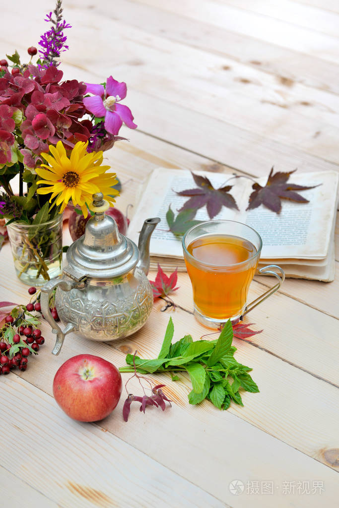 一杯茶, 桌上有红苹果, 五颜六色的花朵和书